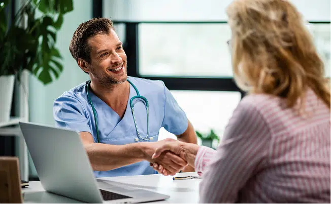 Arzt und Patientin geben sich die Hand